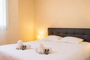 Ein Hotelzimmer mit einem Bett, Kissen, einem Nachttisch mit Lampe und gerollten Handtüchern.