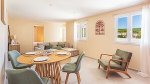 A dining area with a round table, chairs, and a sofa in the background. - L’Oasis Helvétie - Faron View - Welkeys (Toulon)