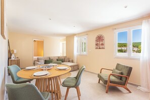 Ein Essbereich mit einem runden Tisch, Stühlen und einer Couch im Hintergrund.