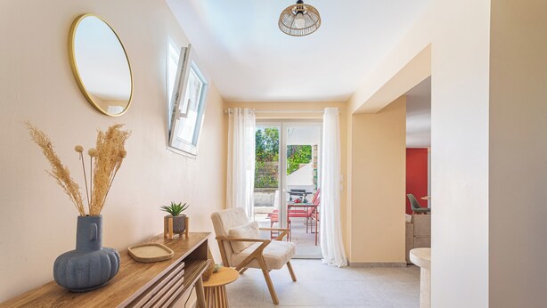 A modern interior with a wooden console table, a white chair, a round table, and a large mirror on the wall. - L’Oasis Helvétie - Faron View - Welkeys (Toulon)