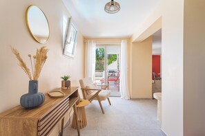 A modern interior with a wooden console table, a white chair, a round table, and a large mirror on the wall. - L’Oasis Helvétie - Faron View - Welkeys (Toulon)