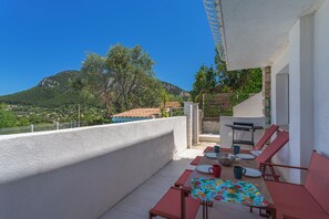Ein Balkon mit Tisch, Stühlen und einem Grill.