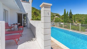 A poolside area with a clear view of the pool, a white building, and a hillside in the background. - L’Oasis Helvétie - Faron View - Welkeys (Toulon)