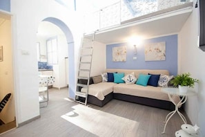 Ein modernes Wohnzimmer mit einer Couch, einem kleinen Tisch mit Pflanze und Kunstwerken an der Wand.