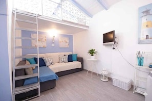 Ein Zimmer mit einem Etagenbett, einem Fernseher, einem kleinen Tisch mit einer Pflanze und Bildern an der Wand.