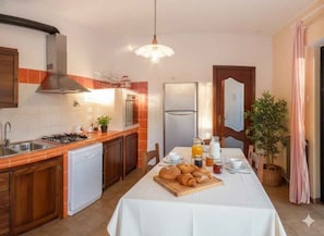 Eine Küche mit Esstisch, gedeckt für das Frühstück, einem Kühlschrank, einer Spüle und einem Herd.