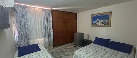 Una habitación con dos camas, televisión, un cuadro y un armario.