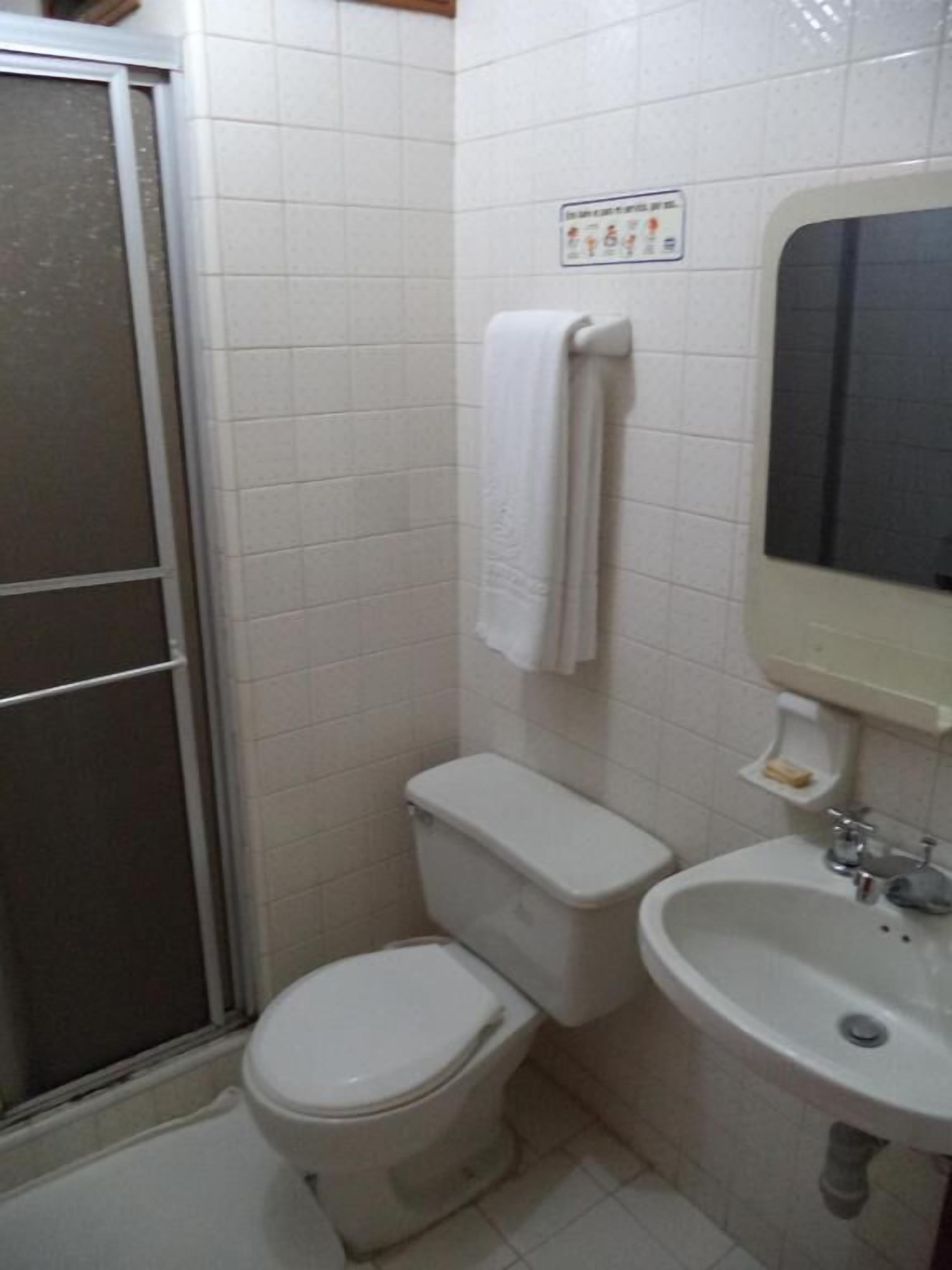 Une salle de bain comprenant des toilettes, un lavabo et un espace douche.