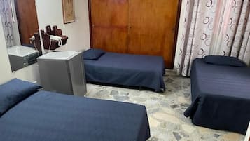 Quarto com duas camas, um guarda-roupa de madeira, uma pequena mesa com uma cadeira e um espelho.