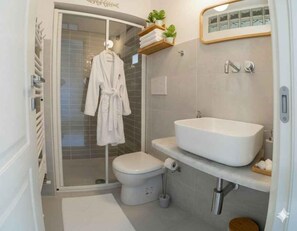 Ein modernes Badezimmer mit einer Duschkabine aus Glas, einer weißen Badewanne und einem Waschtisch mit großem Becken.