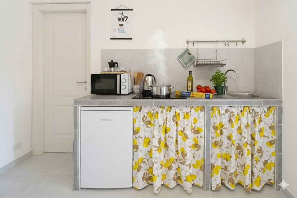 A compact kitchen with a microwave, kettle, and small refrigerator.