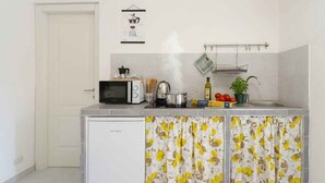 Eine kleine Küche mit Mikrowelle, Wasserkocher und kleinem Kühlschrank.