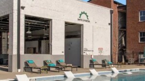 Une piscine avec des chaises longues, un bâtiment sur lequel on peut lire l’inscription « SOUTH & PORTER », et un ciel bleu azur.