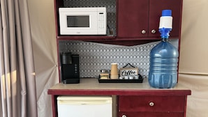 Eine kompakte Küchenzeile mit Mikrowelle, Kaffeeautomat, Wasserspender und kleinem Kühlschrank.