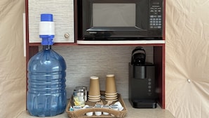 Eine Küchenzeile mit Mikrowelle, Kaffeemaschine, Wasserspender und Wasserkrug.
