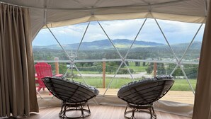A tented room with two wicker chairs, a patterned rug, and a view of a mountainous landscape. - Jasper Gateway Glamping (Hinton)