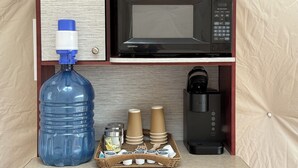 A kitchenette with a microwave, coffee maker, water dispenser, and a water jug. - Jasper Gateway Glamping (Hinton)