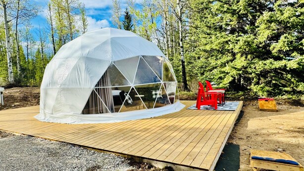 A geodesic dome structure with a wooden deck and red chairs. - Jasper Gateway Glamping (Hinton)