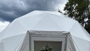A white tent with a door, a welcome wreath, and a doormat. - Jasper Gateway Glamping (Hinton)