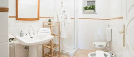 A bathroom with a sink, mirror, shower, toilet, and towel rack.