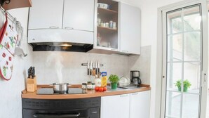 A compact kitchen with a built-in oven, a microwave, and a stove. There is a window with a view of greenery outside. - Studio with air conditioning and terrace (Santo Stefano Al Mare)