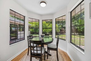 A dining area with a round table, four chairs, and large windows. - Quiet Neighborhood, Fenced Yard, Dog Friendly (Fernandina Beach)