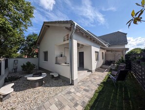 A modern house with a covered patio, a small garden, and a fenced backyard. - Holiday home with Wi-Fi and air conditioning (Siófok)