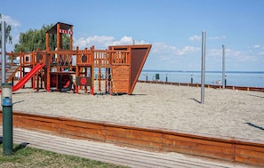 A beach playground with a slide and climbing structures, a wooden boardwalk, and a view of the sea. - Holiday home with Wi-Fi and air conditioning (Siófok)