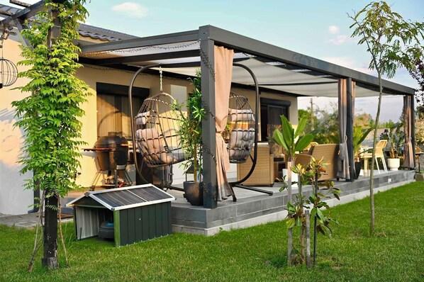 Eine moderne Außenpatio mit Grill, Hängestühlen und einem kleinen Schuppen.