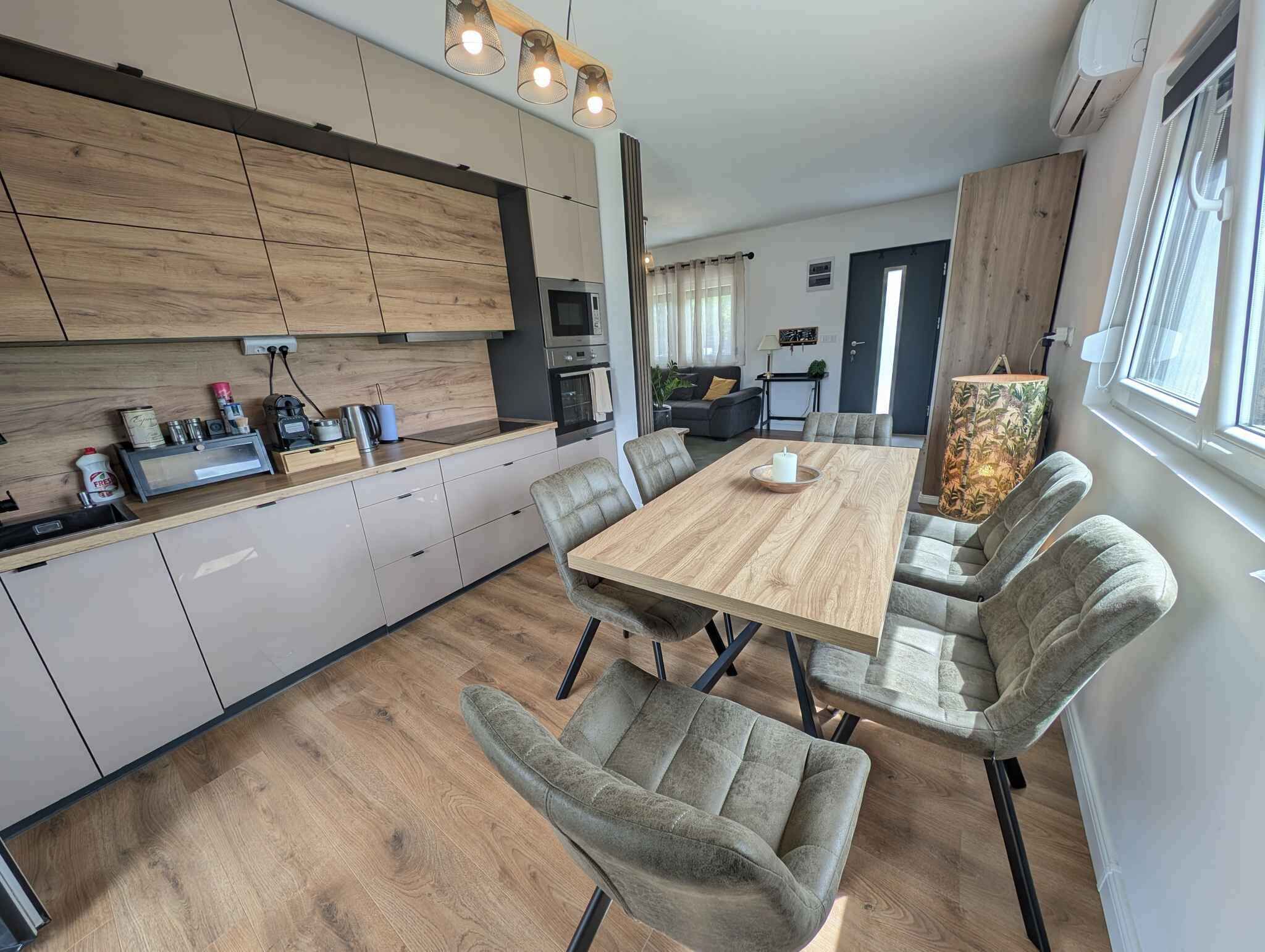 Une cuisine moderne avec un coin repas, des meubles en bois et une grande fenêtre.