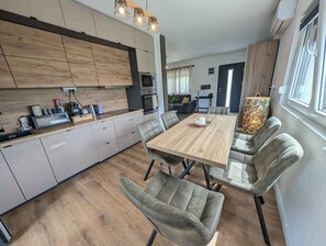 Moderni keittiö, jossa on ruokailutila, puukaapit ja suuri ikkuna.