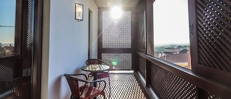Uma varanda com mesa e cadeiras, vista da cidade e parede com padrão.