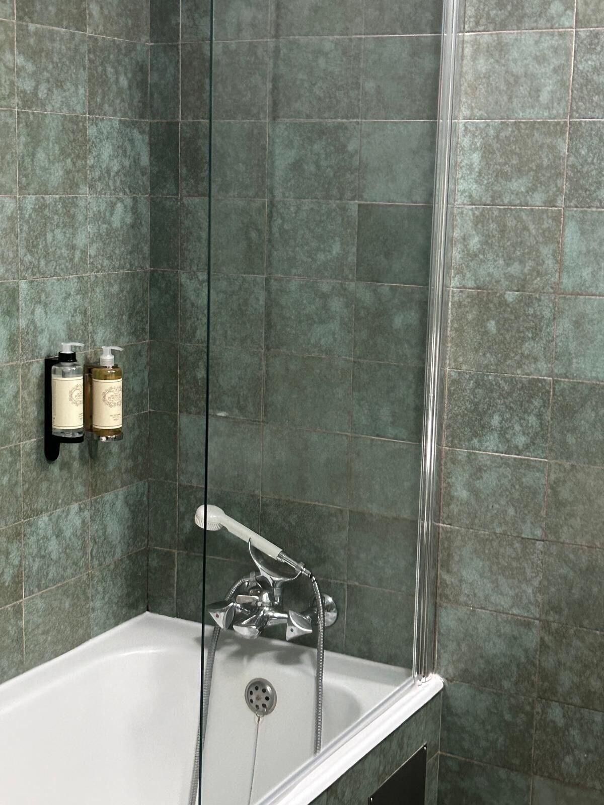 Un baño con bañera, ducha y secamanos.
