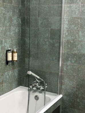 A bathroom with a bathtub, a shower, and a hand dryer.