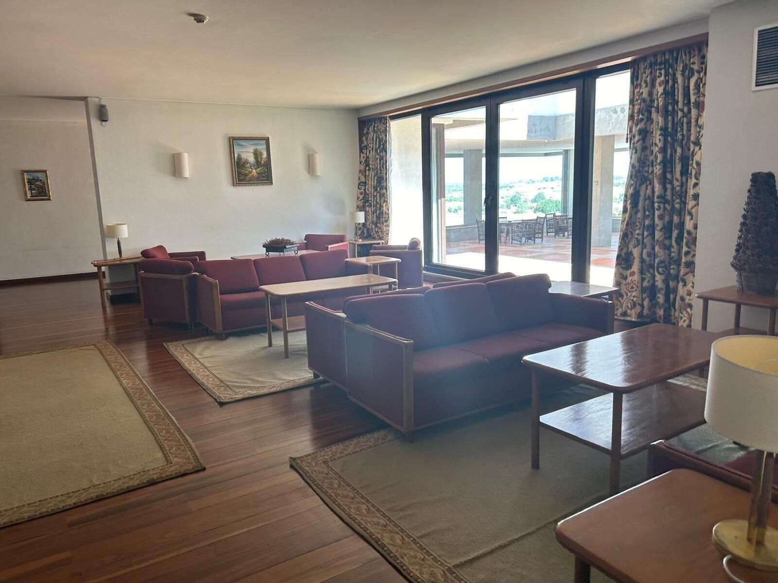 A spacious living room with a sofa set, a coffee table, and a dining table.