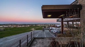 Um edifício com entrada coberta, área de estacionamento e vista para a paisagem ao redor.