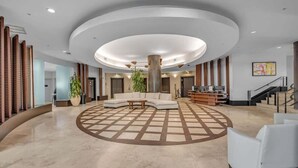 Tilava aula, jossa on keskeinen oleskelualue, portaikko ja vastaanottotiski.