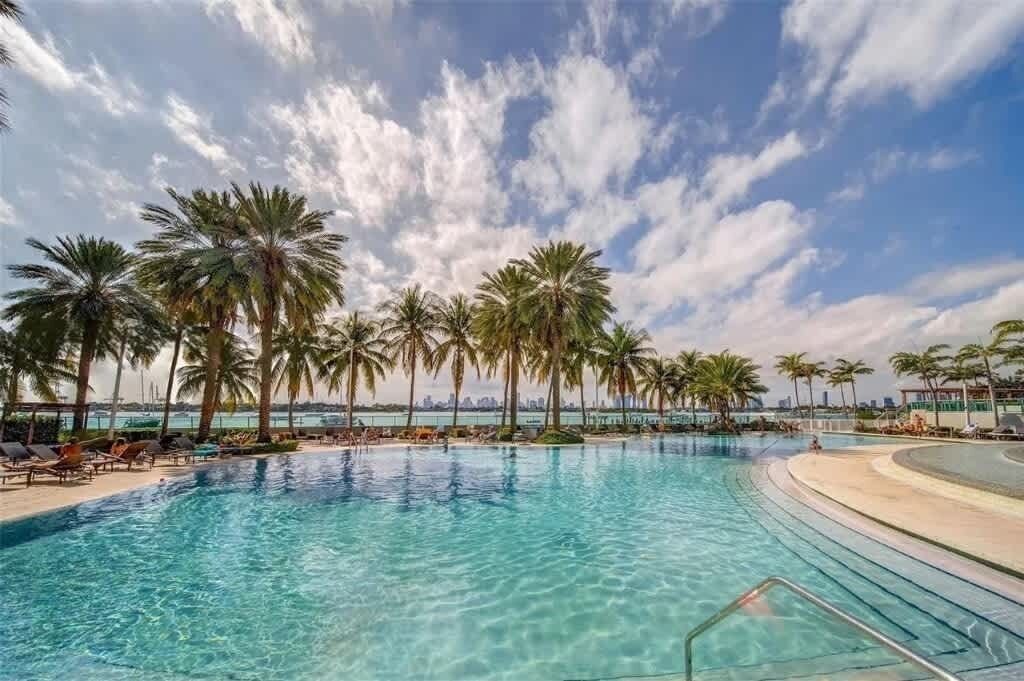 Ein Pool mit Palmen, Liegestühlen und Blick auf die Skyline der Stadt.