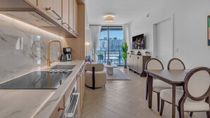 A modern kitchen with a marble countertop, a built-in stove, and a dining area with a table and chairs. - Luxe Wynwood 1BR · Balcony + Rooftop Pool, Miami (Miami)