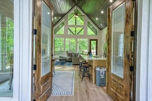 A rustic interior with a high ceiling, wooden beams, and large windows. - New! Twisted Wildflower! Spa, Fire-pit, Foosball! (Broken Bow)