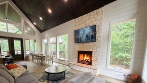 Una sala de estar con chimenea de piedra, un televisor grande montado en la pared y una zona de estar acogedora.