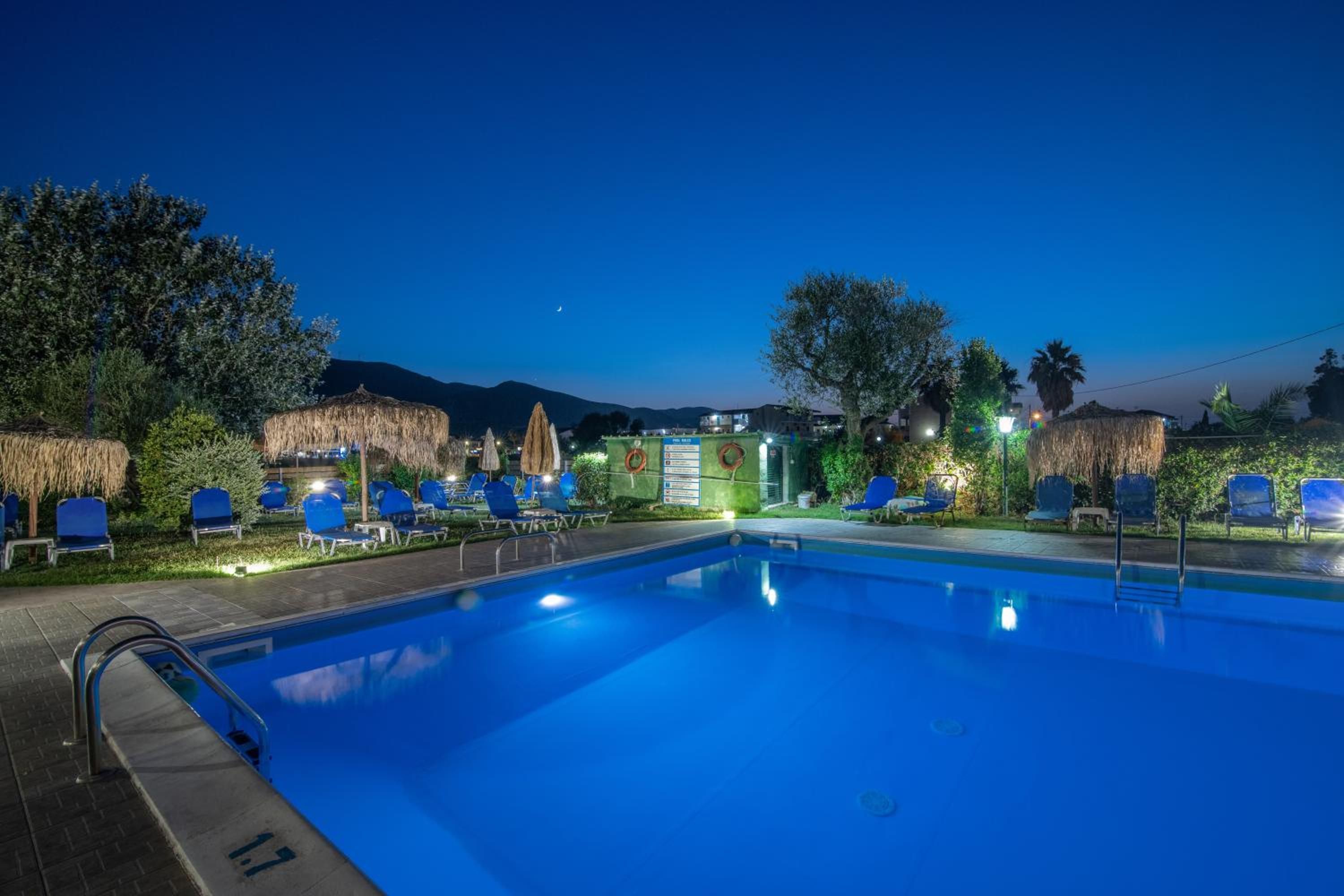 Una piscina con sillas de descanso y un flotador salvavidas, rodeada de árboles y una montaña al fondo.