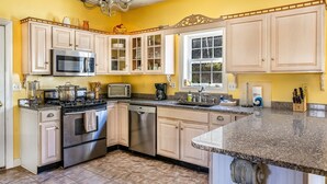 A kitchen with stainless steel appliances, a granite countertop, and light-colored cabinetry.