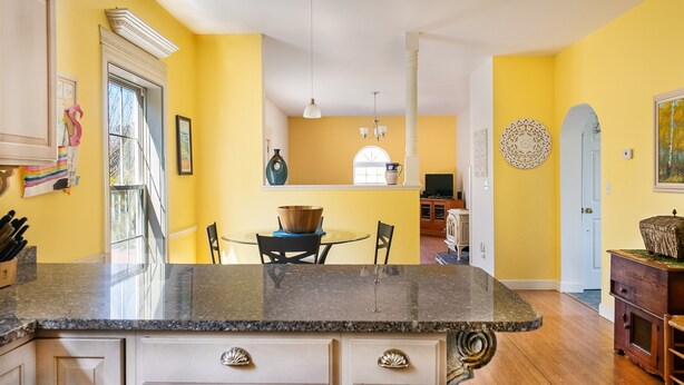 A kitchen with a granite countertop, white cabinetry, and a dining area with a round table and chairs.