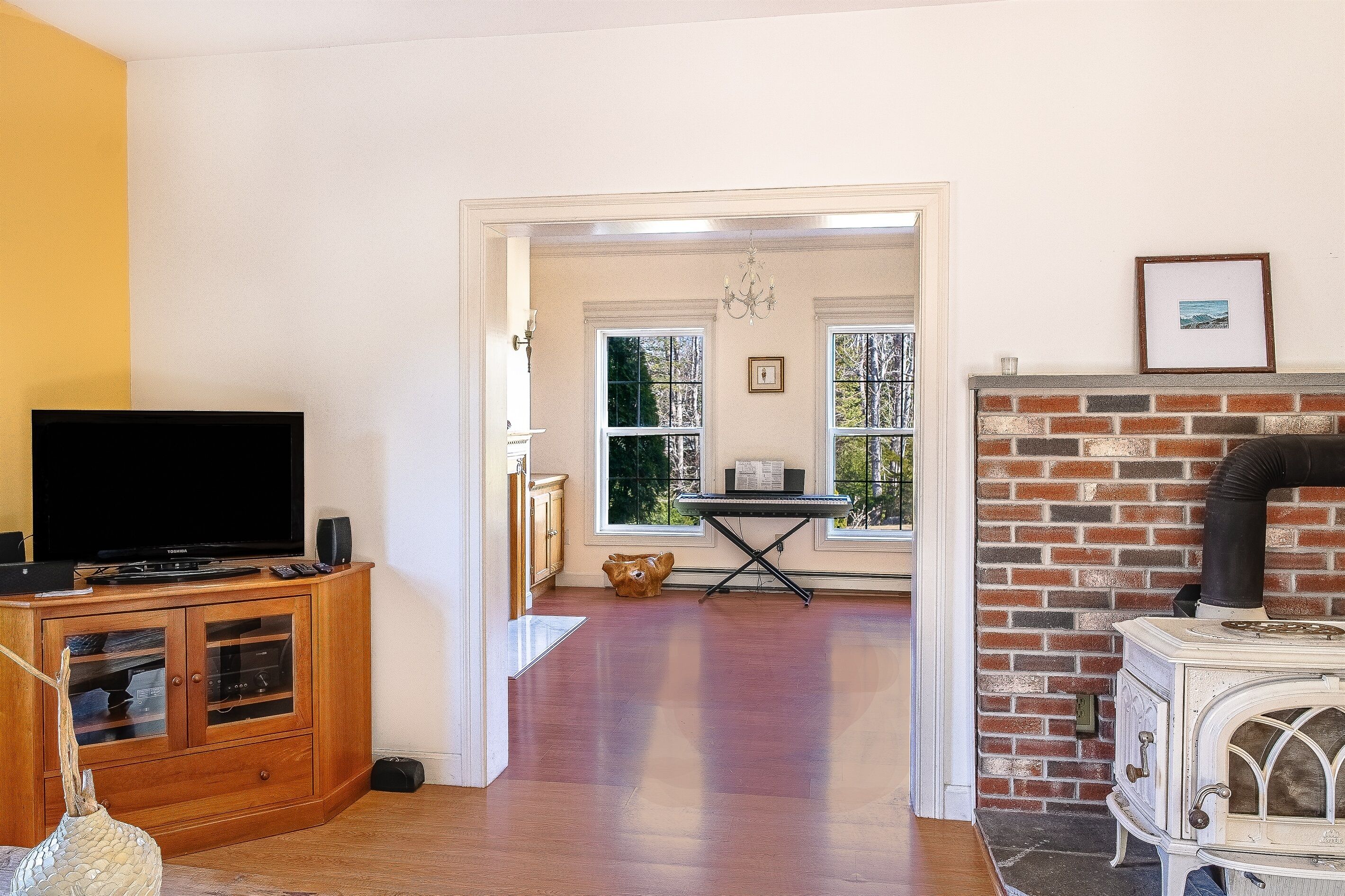 Una sala de estar con televisor, aparador de madera, chimenea y vistas a través de un vano.