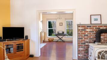 Una sala de estar con televisor, aparador de madera, chimenea y vistas a través de un vano.