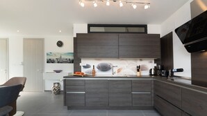 Una cocina moderna con una isla central, armarios de madera oscura y un televisor de pantalla plana montado en la pared.