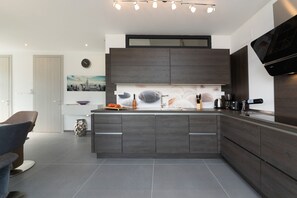 Eine moderne Küche mit einer zentralen Kochinsel, dunklen Holzschränken und einem an der Wand befestigten Flachbildfernseher.