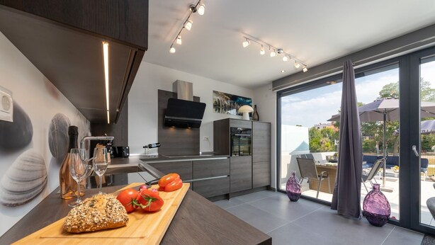Una cocina moderna con encimera de madera, horno empotrado y un amplio ventanal.