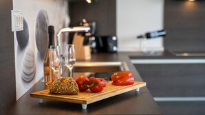 Una cocina moderna con una tabla de madera que sostiene pan, tomates y una botella.